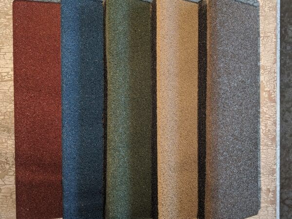 A group of four rolls of carpet in different colors.