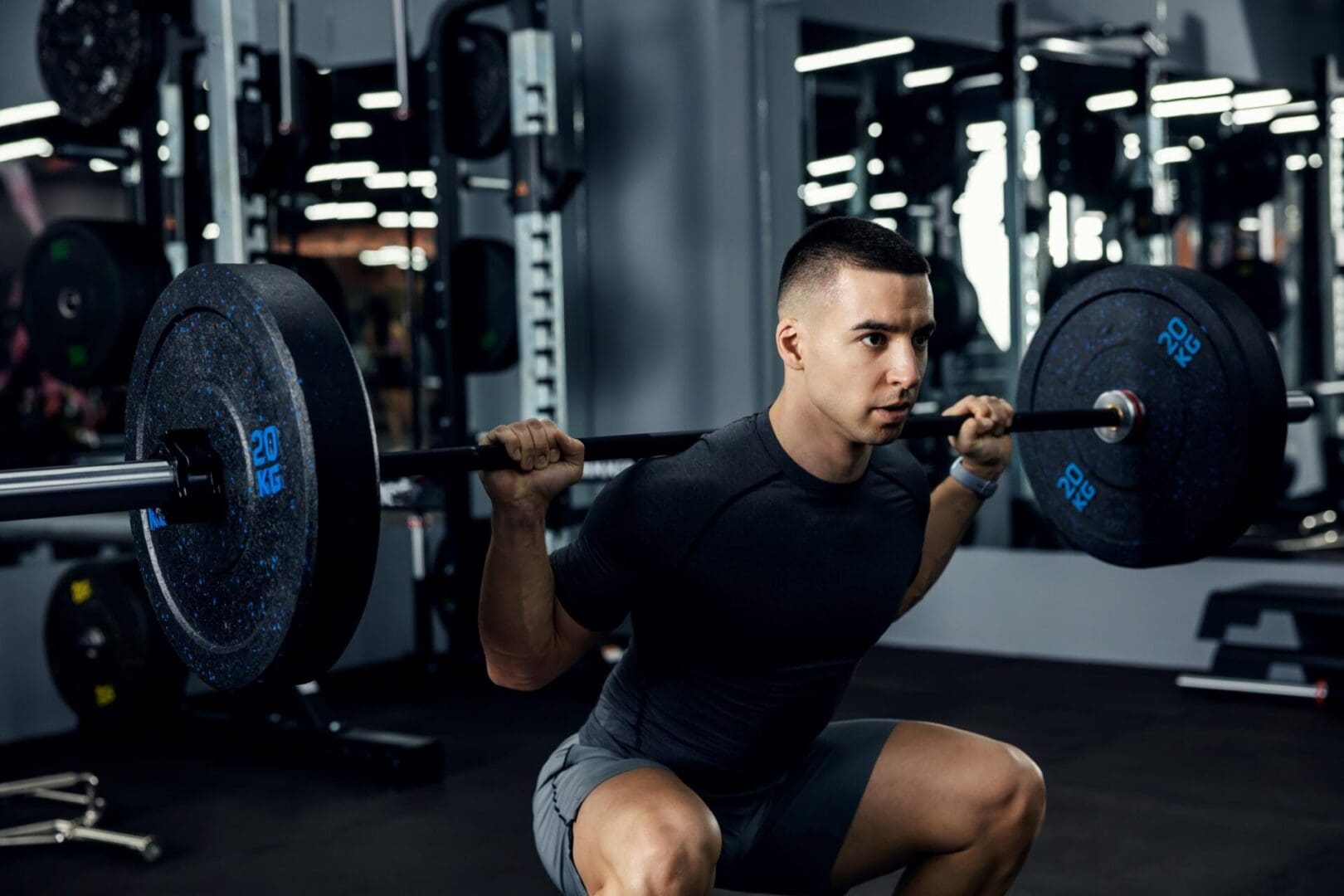 A person is performing a squat with a barbell, utilizing adjustable rubber fitness wedges to enhance stability and form in the gym.