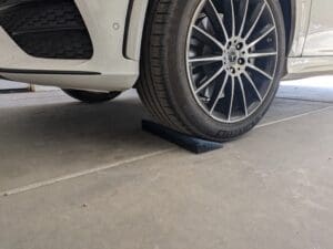 A car is parked in the driveway with its tire on it.